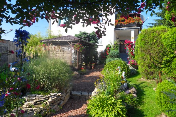 Ścieżka prowadząca przez cały ogród aż do wejścia do domu. Została zrobiona z potłuczonych cegiel, po bokach utworzyłam skalniaki oraz posadziłam ozdobne drzewka.