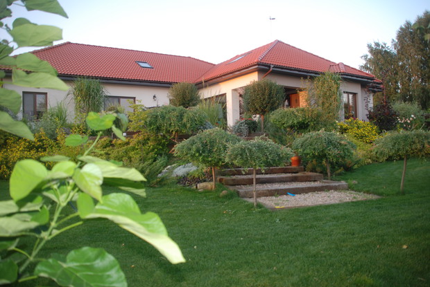 ogród w ciepłych barwach wieczornego słońca, wejście na taras prowadzi przez wygodne szerokie schody z drewna kolejowego