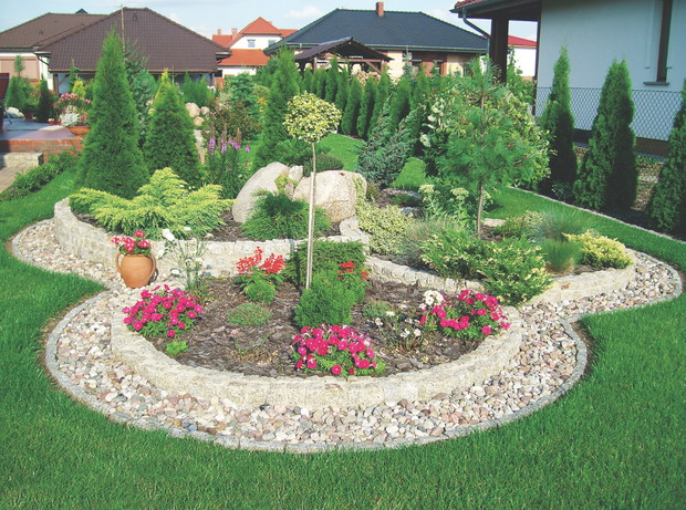 Kręgi z dekoracyjnego żwirku wyznaczają klomb na trawniku.
