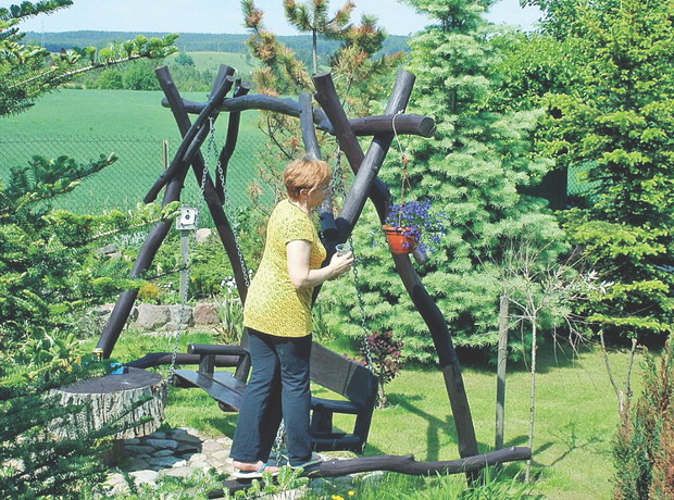 Huśtawka, pomalowana na ciemny brąz, nawiązuje do konstrukcji altanki i do obramowania tarasu 
w domu. 