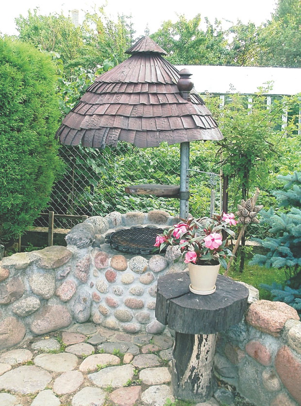 Palenisko na kamiennym grillu chroni niewysokie obramowanie i blaszany dach. 