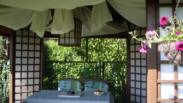 Spojrzenie do środka na lampę wykonaną przeze mnie z drewna i papieru  zawieszoną na łańcuchach, zaś naroża herbaciarni tworzą cztery " trójkątne słupy" o ażurowych ścianach  nawiązujących do kształtu całego ogrodu jakim jest pole trójąta