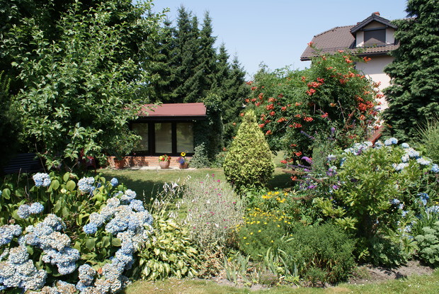 Domek w ogrodzie powstał ze starej pasieki. W miejscu gdzie znajdowały się ule wstawiłem duże okna, przed nimi podest z kostki brukowej na donice z kwiatami. W środku można się napić kawy.