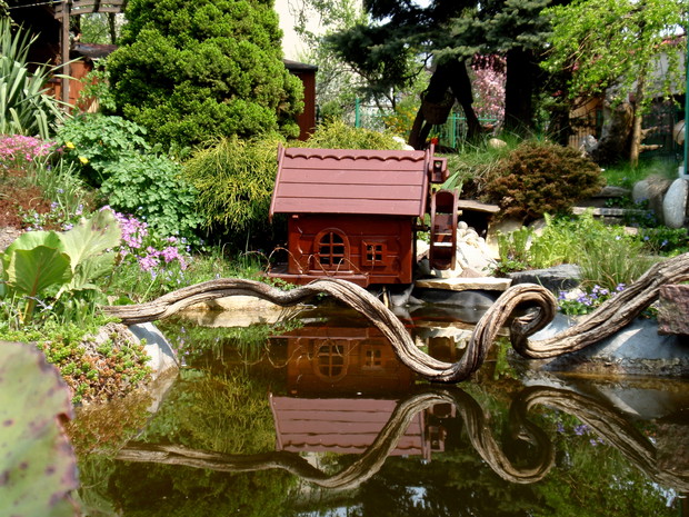 Oczko wodne z drewnianym domkiem wewnątrz którego uruchamia się pompę oraz oświetlenie