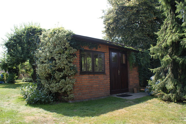 Wejście do domku w ogrodzie. Tylna część starej pasieki pozostała bez zmian - oryginalne stare drzwi i okno mają kilkadziesiąt lat. Uroku domkowi dodają oplatające go bluszcze (w sumie kilka gatunków).