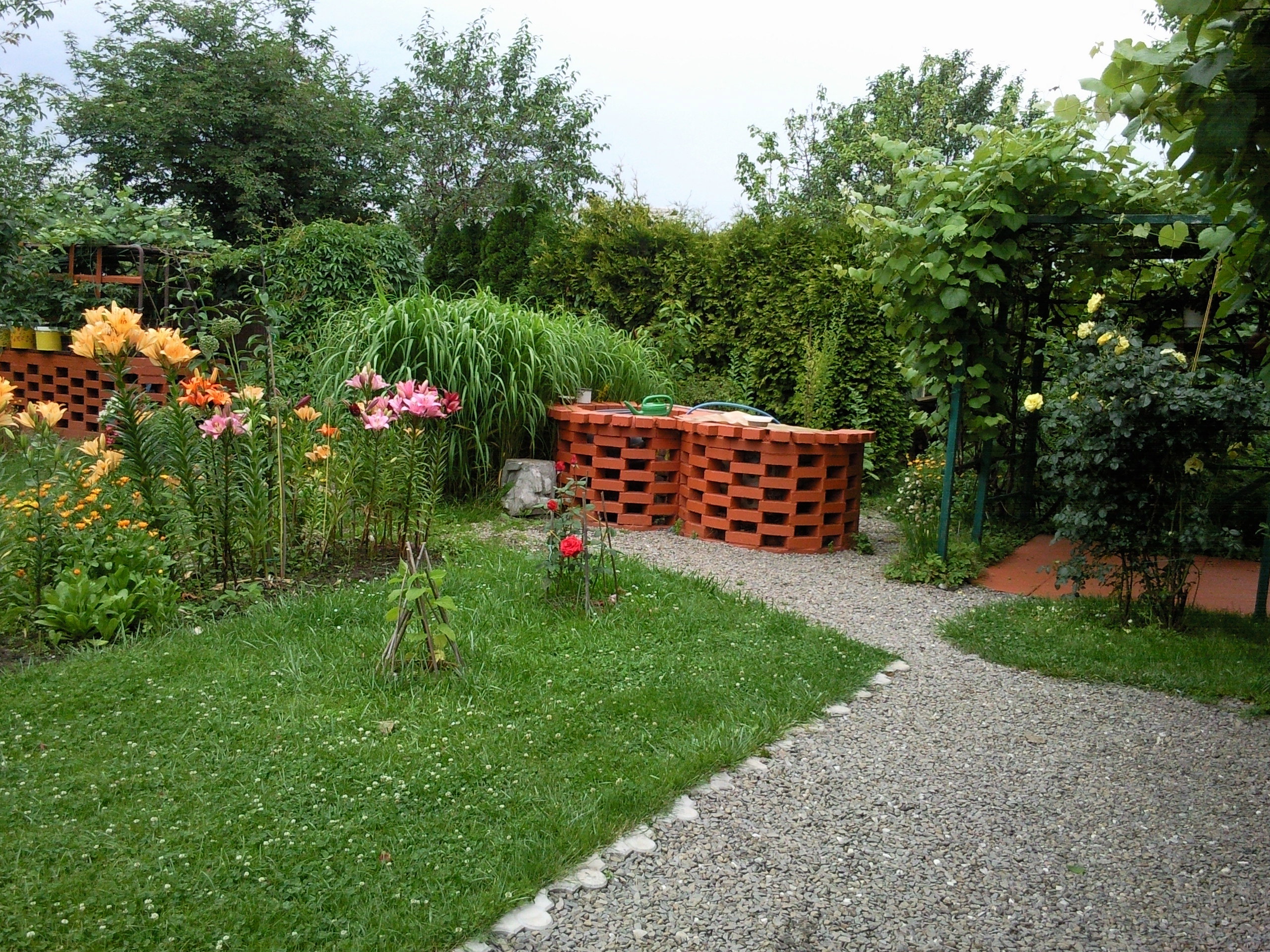 W tylnej części działki w jednym rzędzie ustawiony kompostownik, oczko wodne, obudowa studni z grillem i pergola na wypoczynek zacieniona winoroślą.