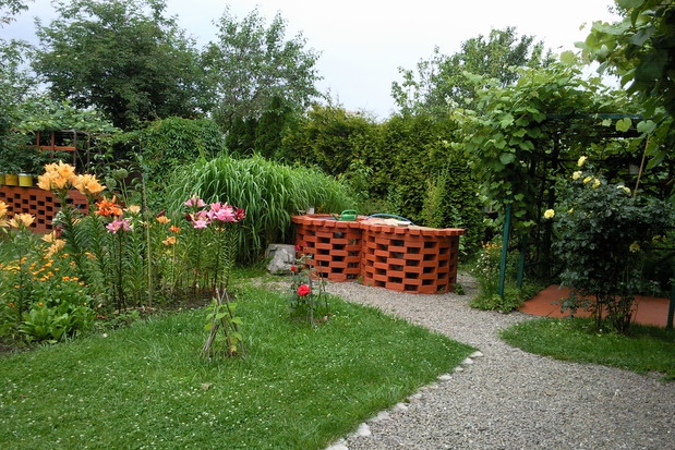 W tylnej części działki w jednym rzędzie ustawiony kompostownik, oczko wodne, obudowa studni z grillem i pergola na wypoczynek zacieniona winoroślą.