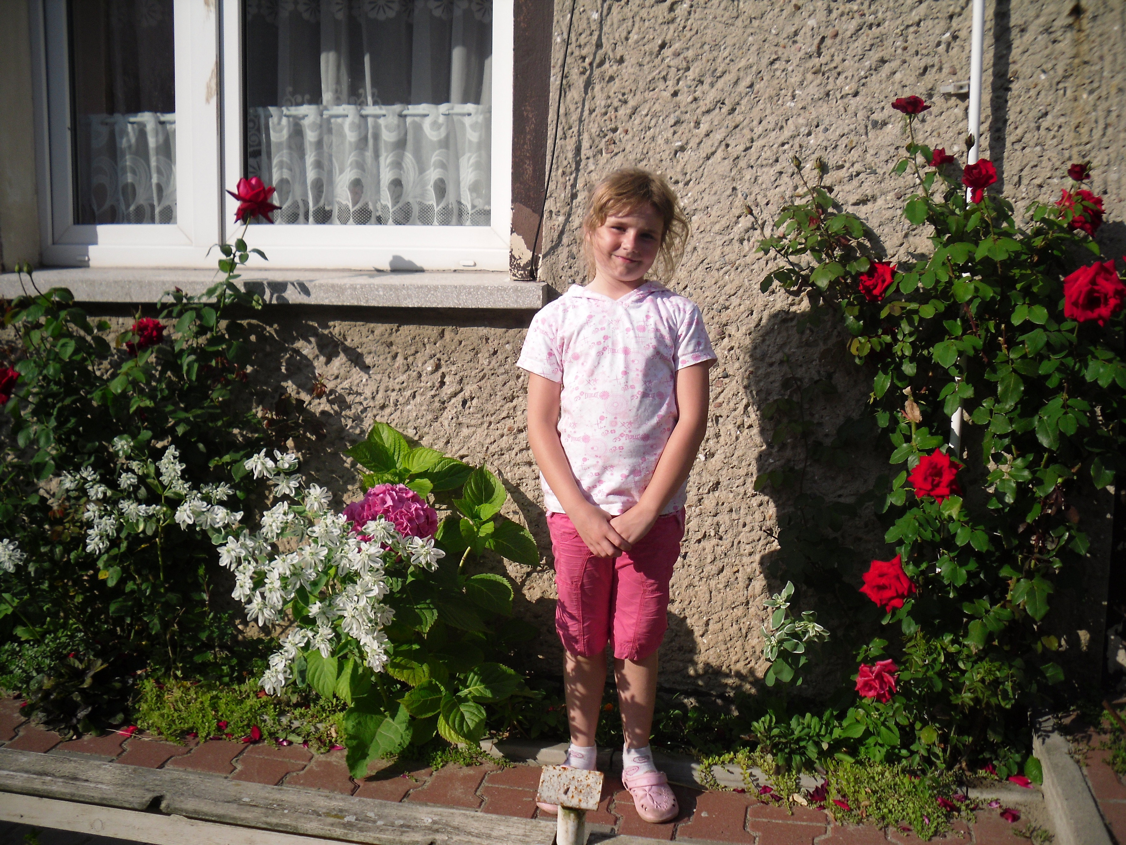 Moja wnuczka u mnie na wakacjach przy rozach kolo domu