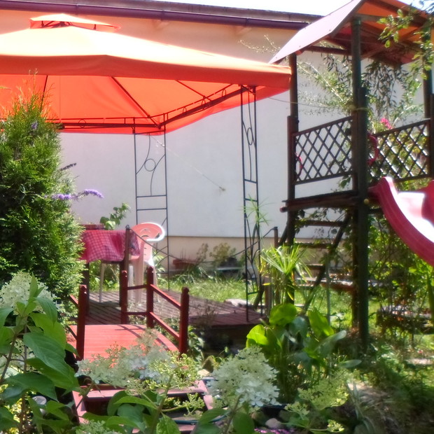 plac zabaw w miniaturze wraz z kładką nad małym oczkiem wodnym w którym pływają karasie.