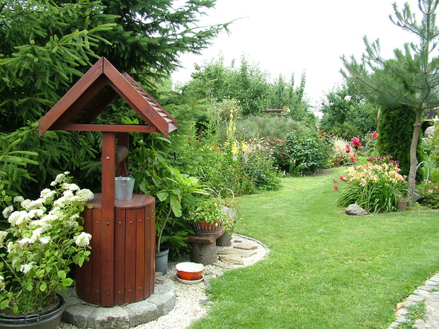 Jeden z widoków, jaki wyłania się za magicznym wejściem, lewa strona ogrodu, ze studnią i wieloma rabatami kwiatowymi