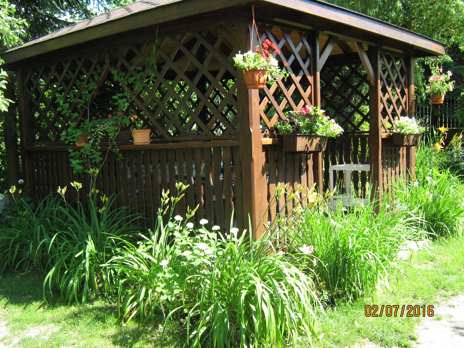 Altana, którą porasta wiciokrzew i otaczają kwitnące liliowce, hortensje i malwy.
