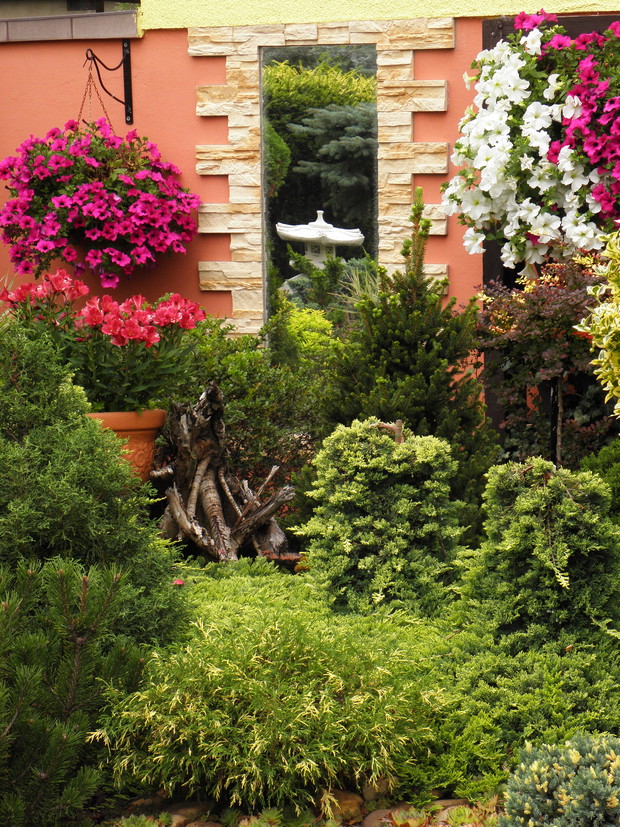 lustro na ścianie powoduje, że odbijają się w nim zakątki ogrodu.....zależy z jakiego miejsca w nie się zagląda....Jak Alicja w Krainie Czarów.....