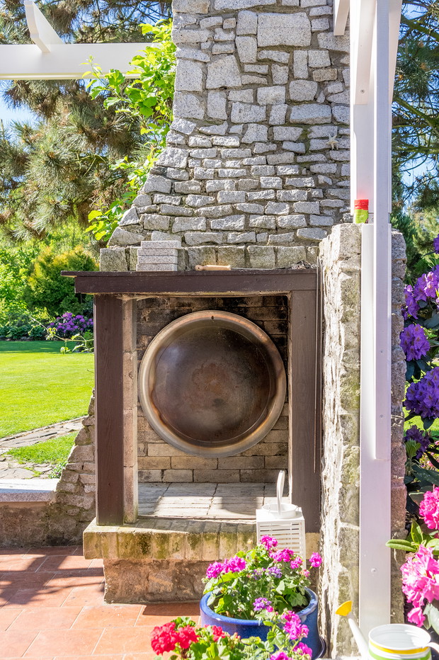 Kominek z granitowych kamieni i cegieł na tarasie to miejsce wieczornych rozmów przy ogniu.