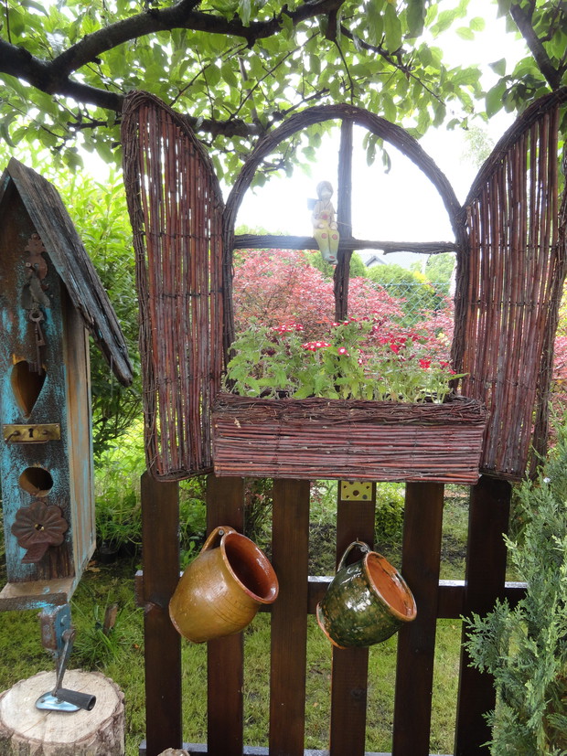 Przy oknie stoi budka na kurzej łapce (ręcznej wiertarce)... a pod wiszą stare gliniaki... 