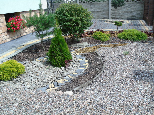 Prostokątny ogródek przed domem. Rosną tu żurawki, kosodrzewina, wiśnia japońska, tuja Mirjam, cyprysiki groszkowe Sungold, jodła koreańska, ostrokrzew szczepiony na pniu.