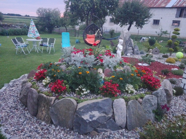 Skalniak a na nim begonie boberek,aksamitka,mrozy ,kaktusiki na gornej części znajduje się juka pelargonie ,wokół kwiatow usypane kamyczki