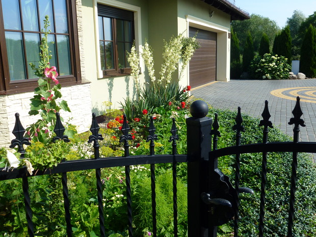 Oczko z jukami, różami, barwinkiem przed domem. 