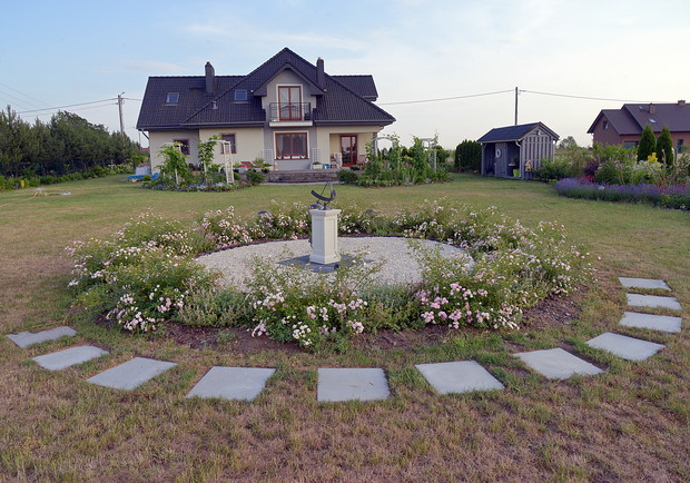 Elementy betonowych płyt w rozmiarach 50x50 cm podkreślają owal tonda które zostało przygotowane pod zegar słoneczny. Element osi następnego widoku. Okno tarasowe, zegar i wejście do warzywniaka znajdują się w jednej linii. Tak projektują ogrodnicy z hist