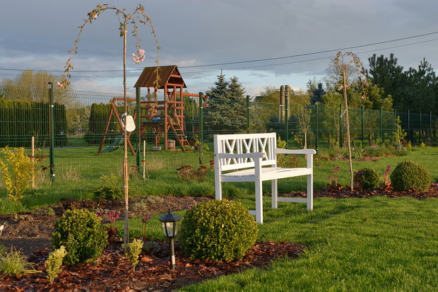 Wiosenna ławeczka w aranżacji z nowymi nasadzeniami. Rośliny już robią tło, za chwile powstanie romantyczny zakątek.