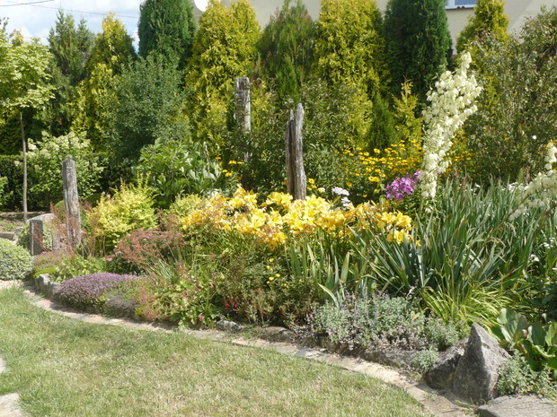 Rabata w pełni lata. Widać kwitnące liliowce, płomyki, juki i macierzanki.