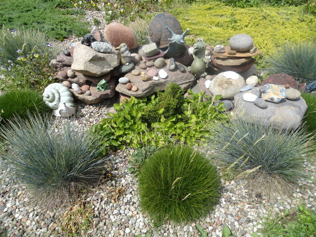 polne kamienie i figurki ogrodowe wśród konstelacji traw.