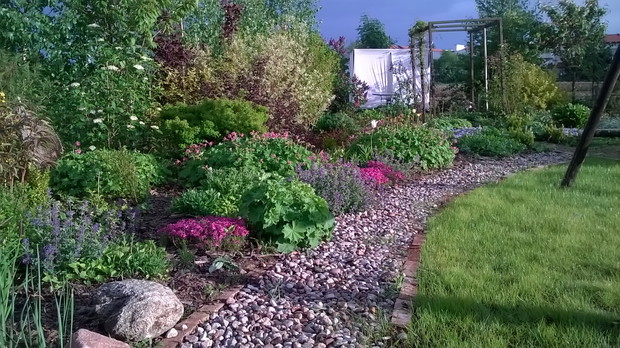 W ogrodach wiejskich sprawdzają się naturalne materiały- kamienie, drewno, cegła.