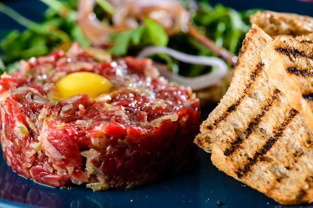 Dish with beef tartare, tomatoes and leaves in a restaurant, clo