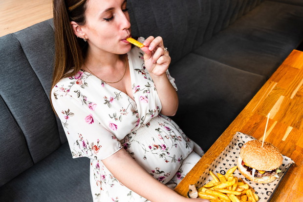 Hamburger pregnancy girl eat. Pretty happy pregnant woman eating tasty burger. Junk food concept.