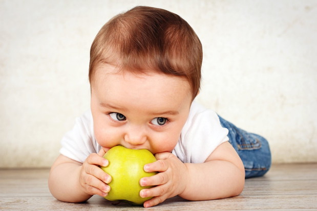Hungry little baby boy eating apple