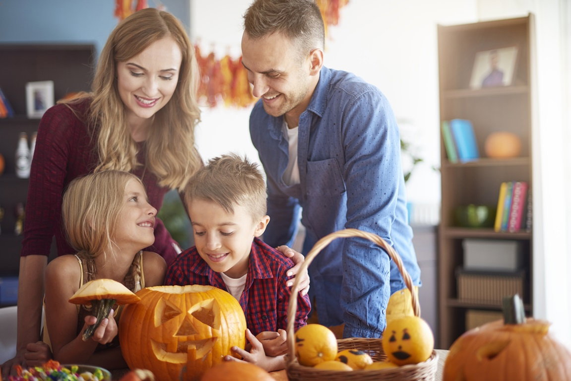 Rodzice z dziećmi wycinaja dynię na Halloween