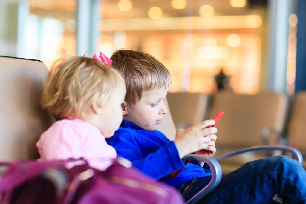 Chłopiec i dziewczynka siedzą wpatrzeni w ekran smartfonu