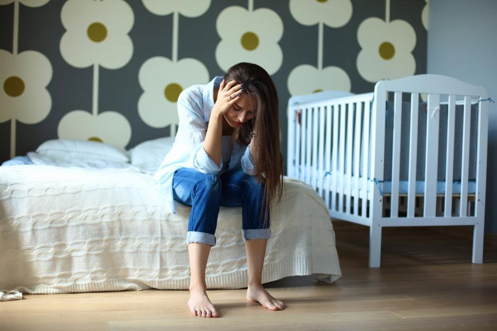 Zmęczona młoda mama siedzi na łóżku