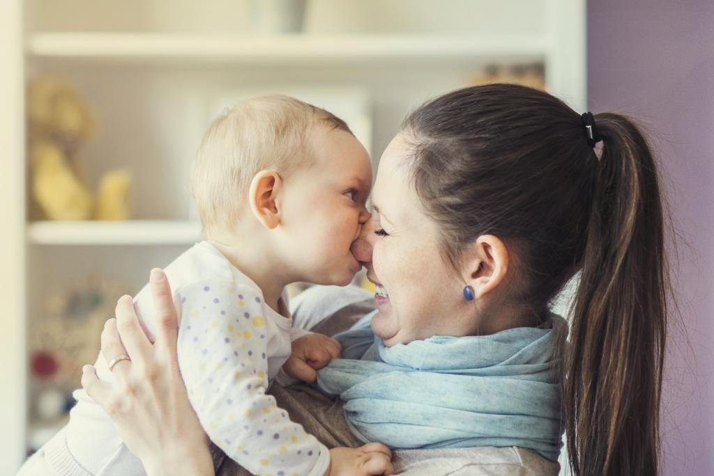 Uśmiechnięta mama trzyma w ramionach córeczkę