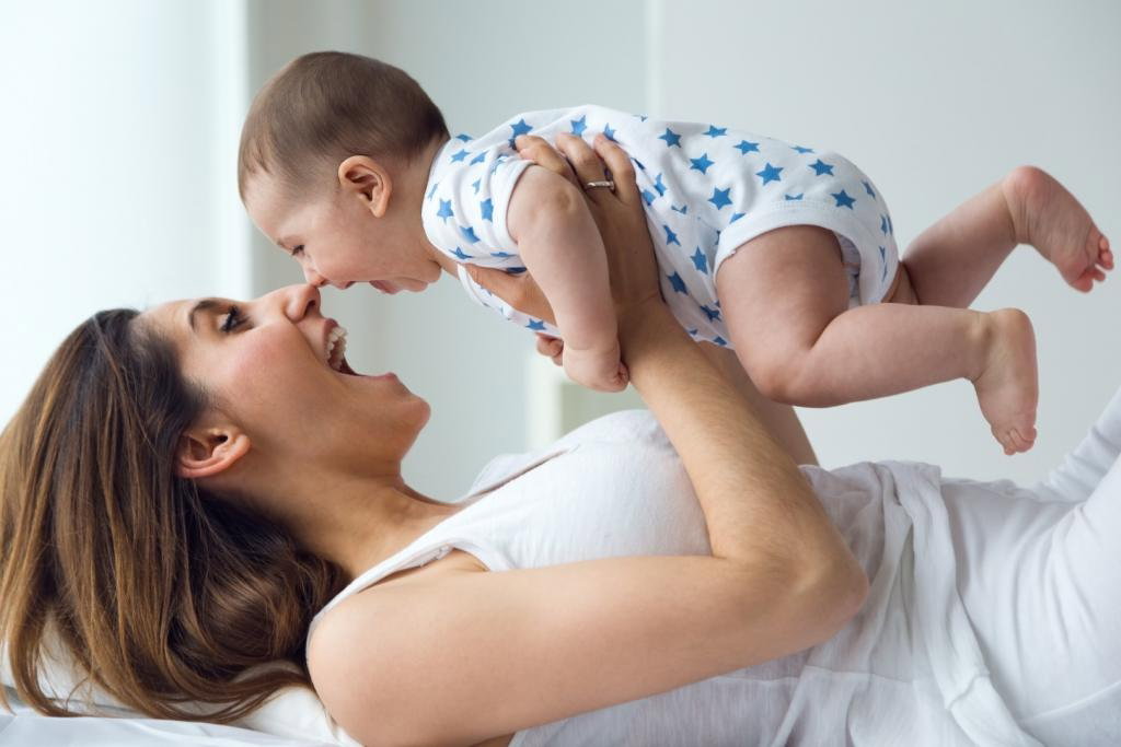 Uśmiechająca się mama bawi się z niemowlakiem