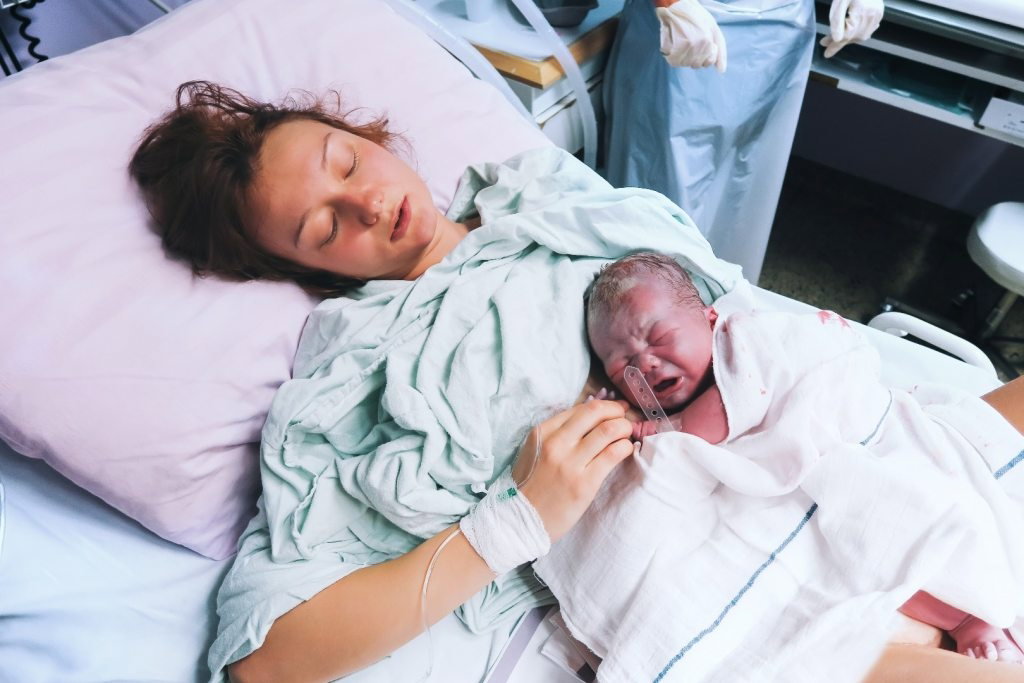 Młoda mama w szpitalu z noworodkiem po porodzie ze znieczuleniem