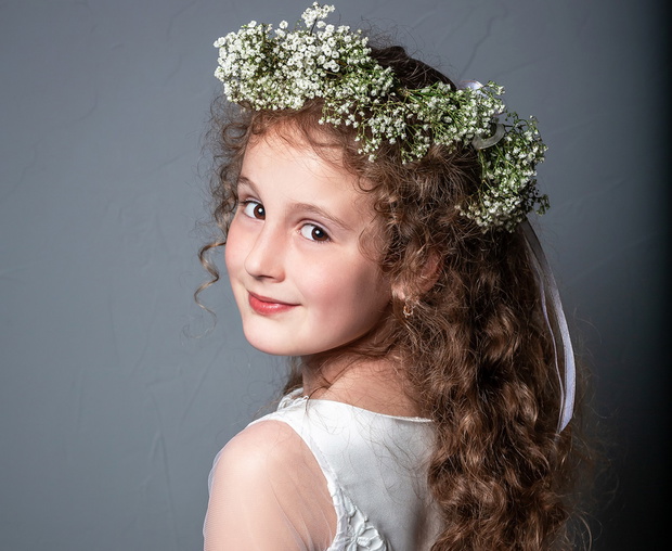 Portrait of cute little girl on white dress and wreath of first holy communion. First Communion Day. Studio photo