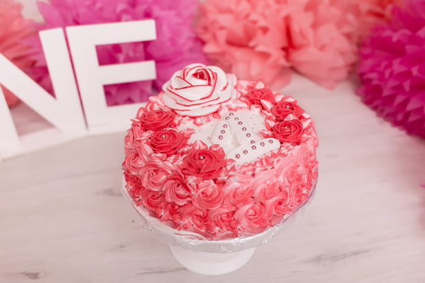 Photo zone with paper garlands, balloons, paper balls, pom poms, confetti and cream cake. Birthday cake. Smash cake. One year. Pink, white, rose colors