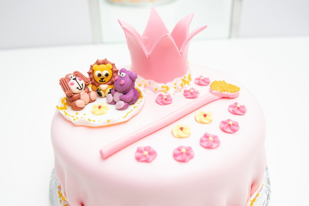 pink cake of a little princess with a crown and animal figures. Birthday one year old. holiday concept.