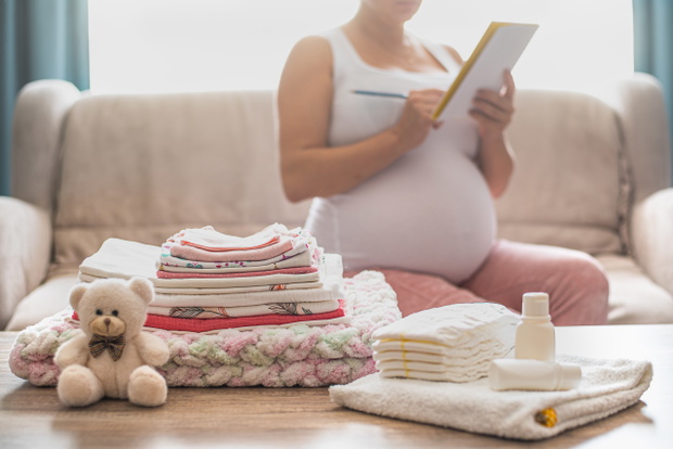 Pregnant woman is getting ready for the maternity hospital, packing baby stuff.
