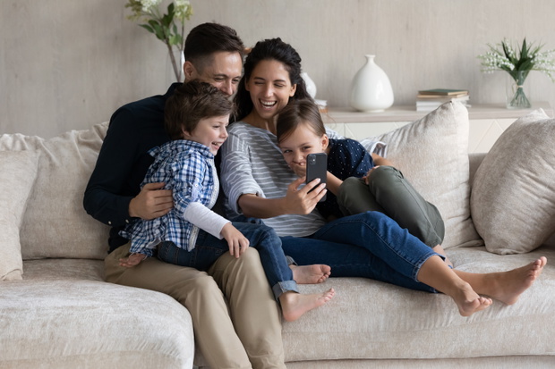 Cheerful family couple and excited happy children resting on sofa