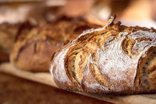 Sourdough bread with crispy crust on wooden shelf. Bakery goods