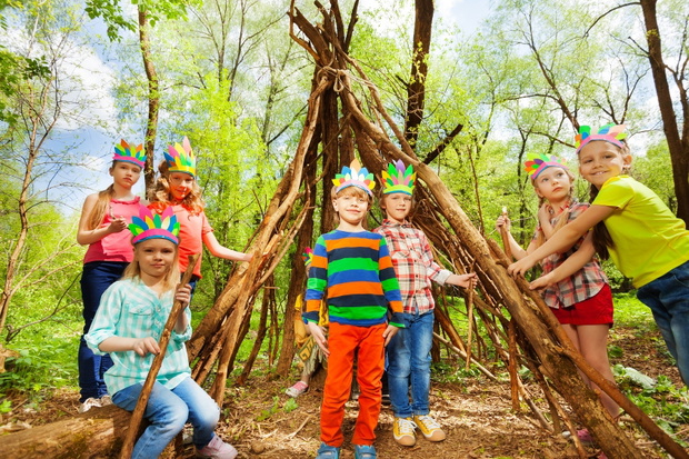 Happy kids building Injun's wigwam in the forest