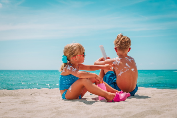 sun protection, little girl and boy with sun cream at beach