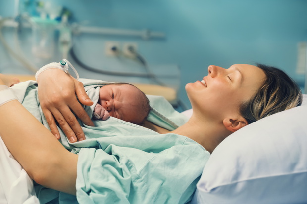 Mother and newborn. Child birth in maternity hospital. Young mom