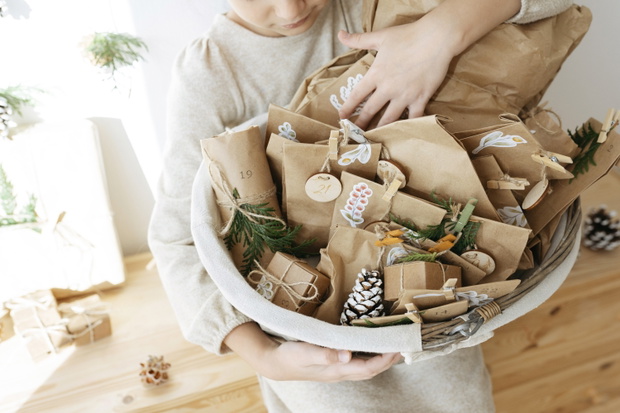 Girl holding basket of advent calendar gifts at home