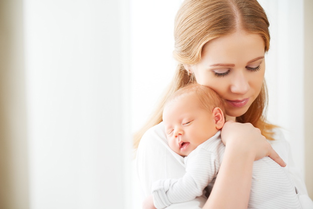 newborn baby in tender embrace of mother
