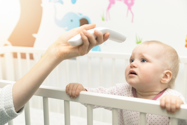 mother check the temperature of baby with non contact thermometer