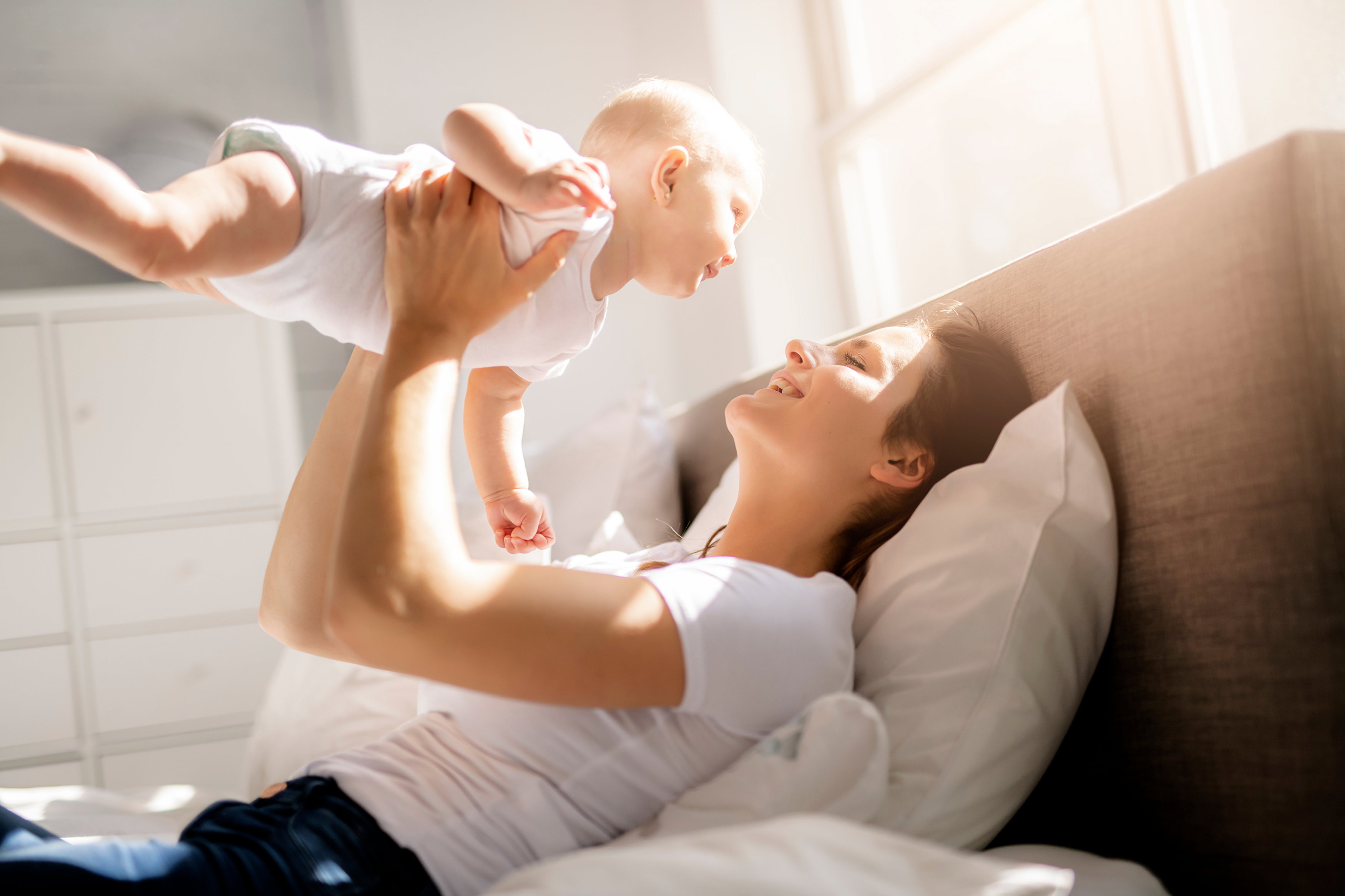 mother with baby on bed having good time
