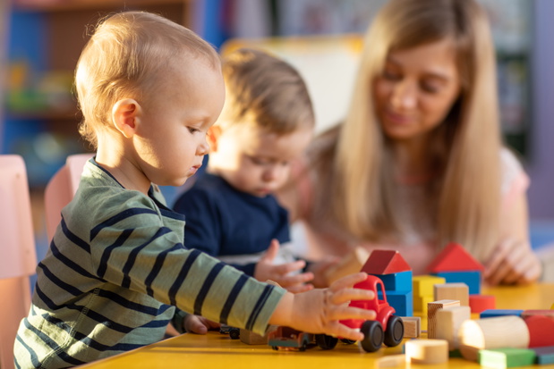 Preschool teacher and cute kids play in kindergarten