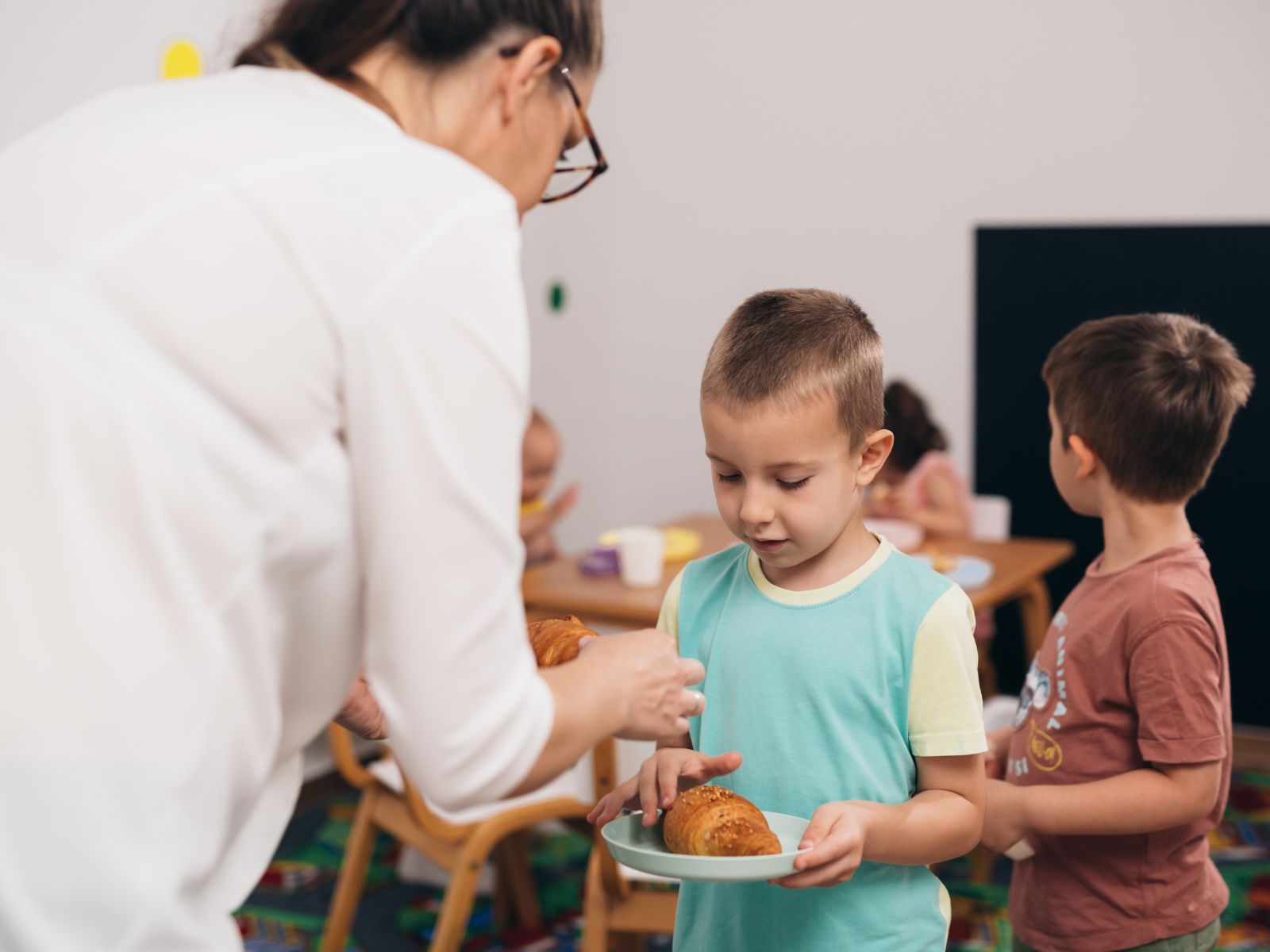 nauczycielka w przedszkolu uczy dzieci samodzielności